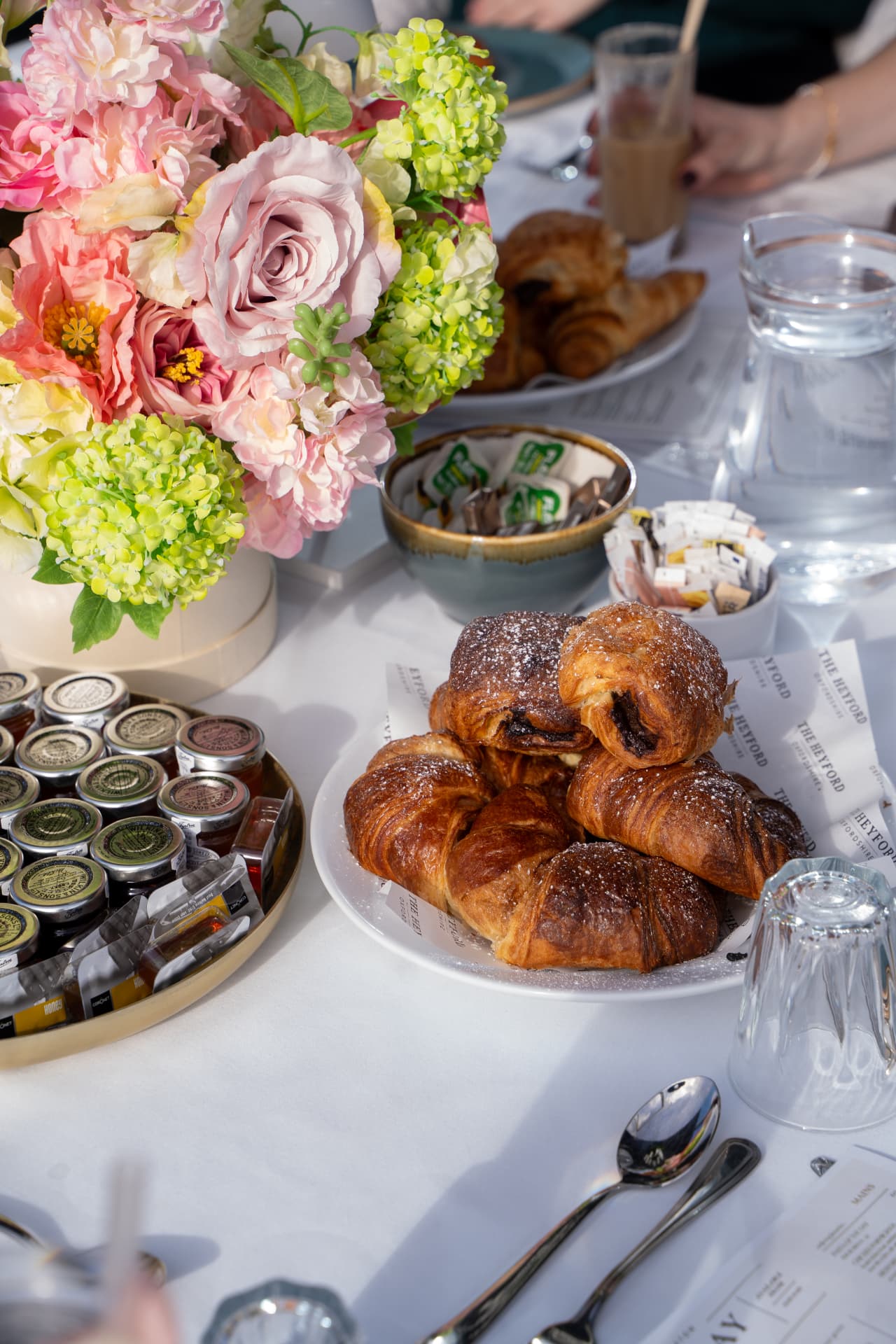 Pastries and croissants on a restaurant table with flowers