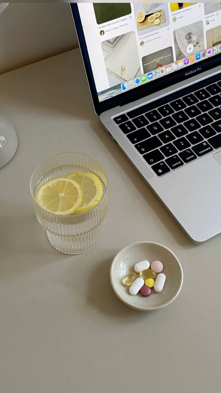 Wellness supplements and lemon water on a desk with a laptop