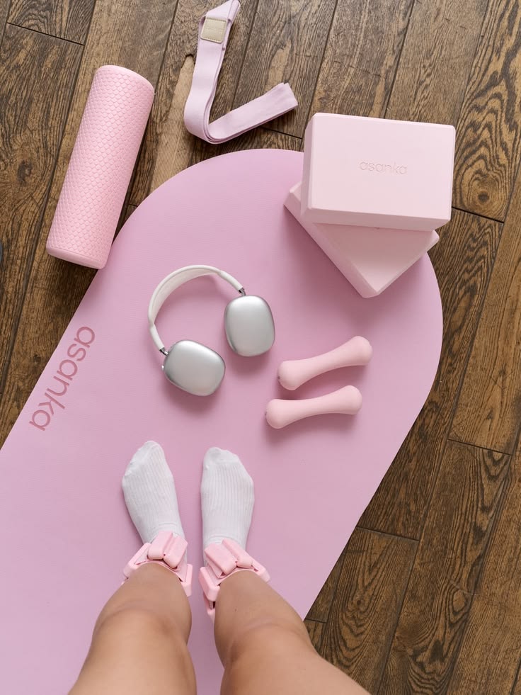 Pink pilates mat with dumbbells, headphones and ankle weights